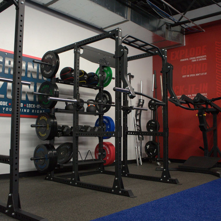 Gym equipment including a power rack with weights and resistance bands against a red wall.